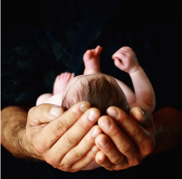 Two hands holding a baby