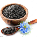 A bowl and spoon containing small black seeds and a blue flower