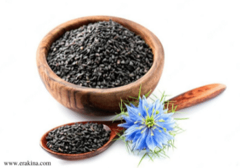 A bowl and spoon containing small black seeds and a blue flower